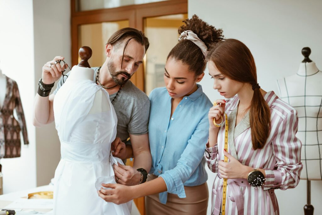 Designers masterpiese. Group of fashion designers measuring dress